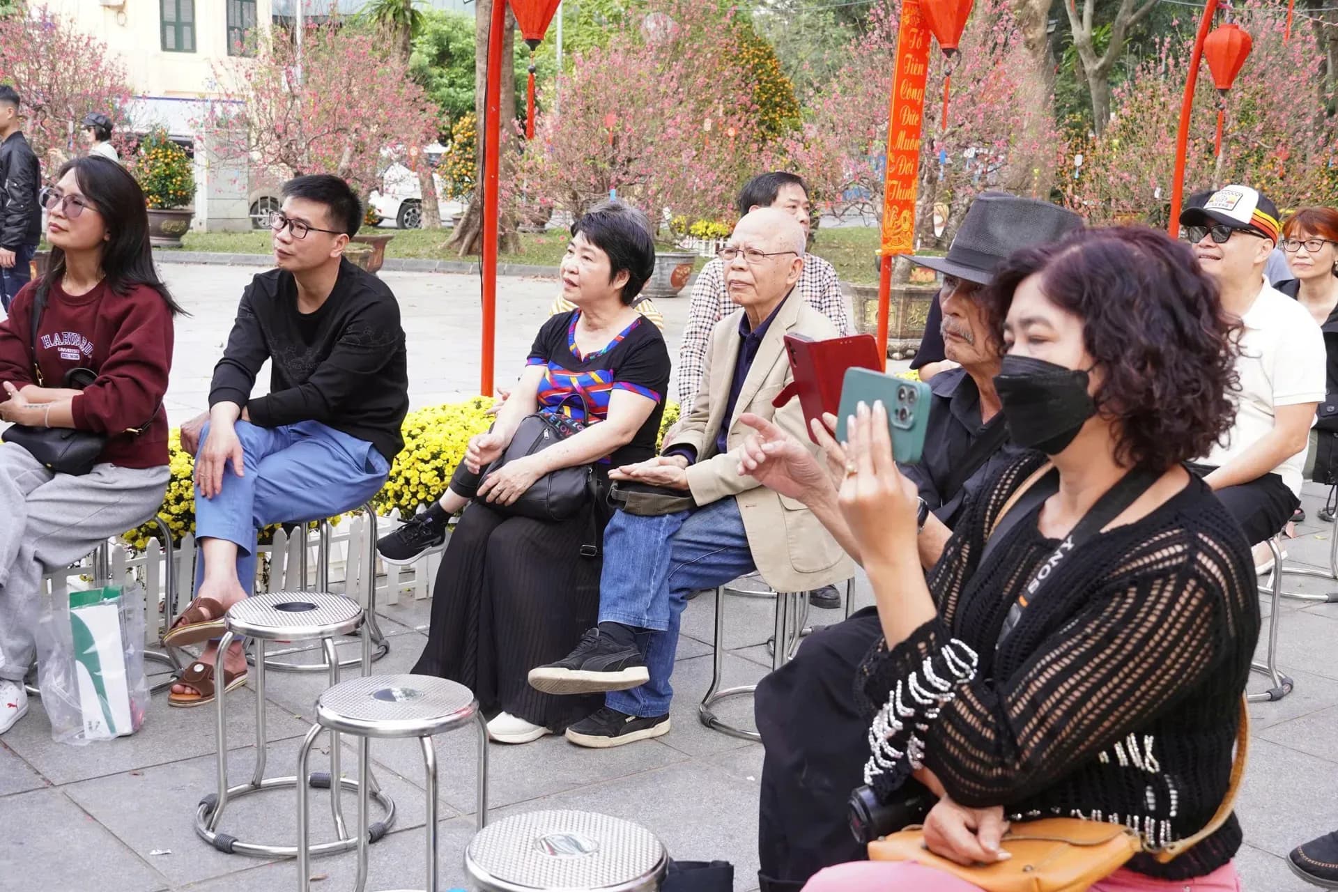 Người dân và du khách ngồi thưởng thức buổi biểu diễn âm nhạc ngoài trời, tạo nên không gian cộng đồng sống động trong mùa xuân đô thị.