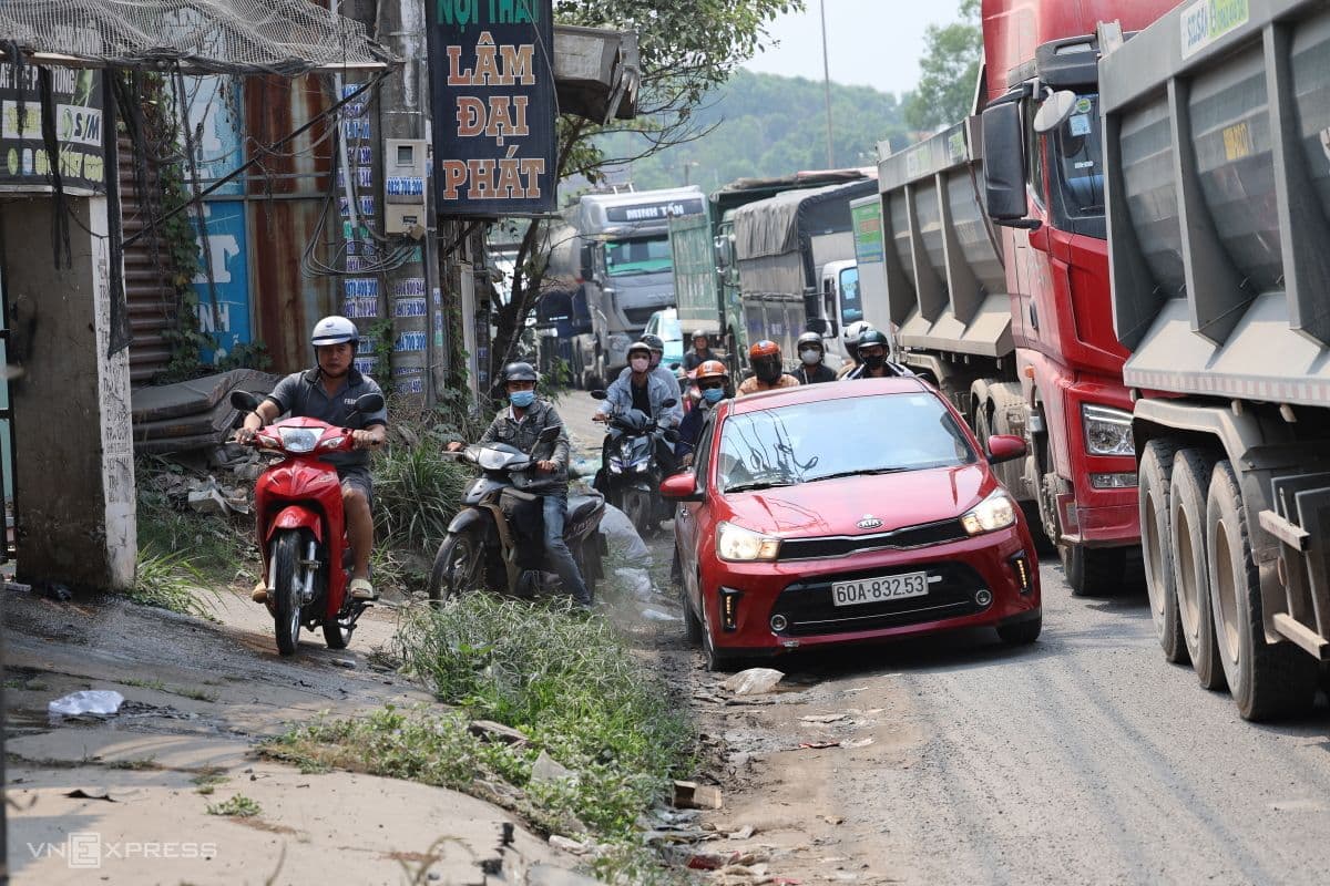 Người dân và phương tiện di chuyển khó khăn trên đoạn đường xuống cấp cạnh Quốc lộ 51 đang thi công, thể hiện ảnh hưởng đến đời sống hằng ngày.