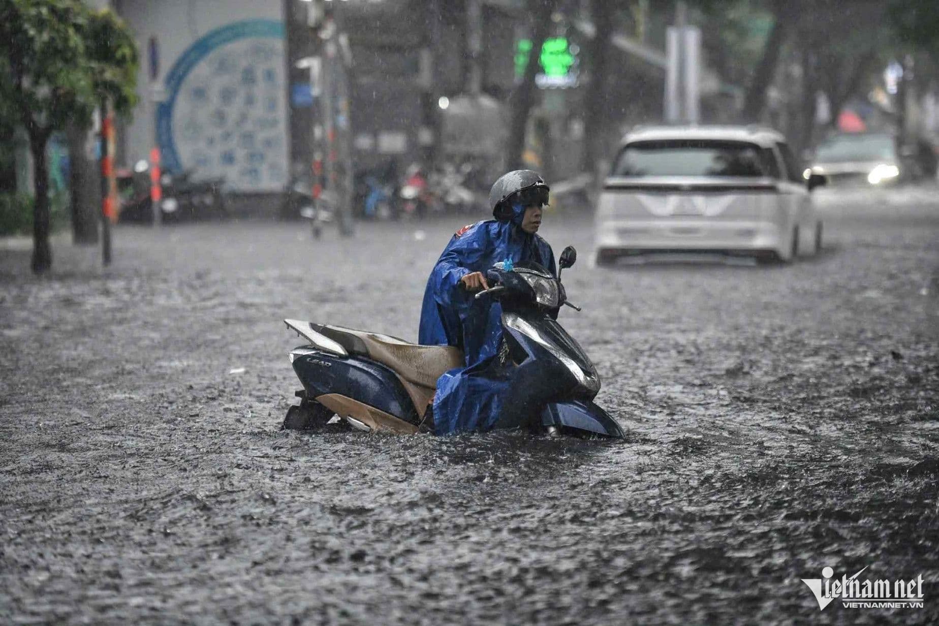 Người dân Việt Nam di chuyển trên đường phố ngập lụt do mưa lớn, thể hiện sự thích nghi với thời tiết khắc nghiệt.