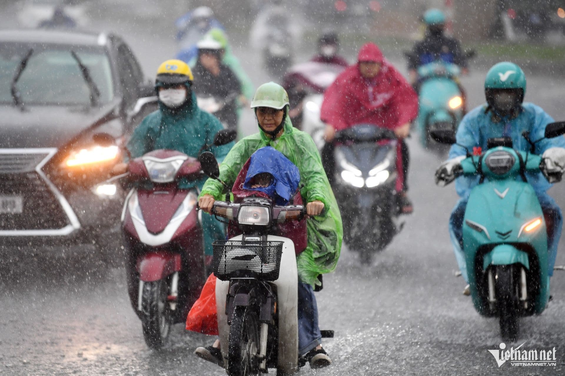 Người dân Việt Nam đi xe máy trong mưa lớn, phản ánh thời tiết khắc nghiệt và tác động đến đời sống hàng ngày.