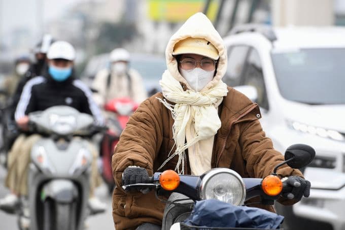 Người dân Việt Nam mặc áo ấm, khăn choàng và khẩu trang đi xe máy trong đợt không khí lạnh bất thường ở miền Bắc.