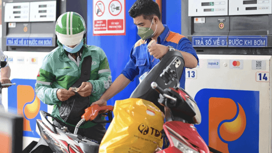 Người dân đổ xăng tại trạm xăng, với thông tin về Quỹ bình ổn giá xăng dầu, thể hiện gánh nặng chi phí nhiên liệu.