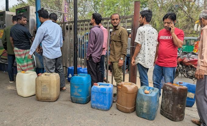 Người dân xếp hàng chờ mua xăng với các can chứa nhiên liệu, phản ánh gánh nặng chi phí sinh hoạt và sự khan hiếm nhiên liệu.