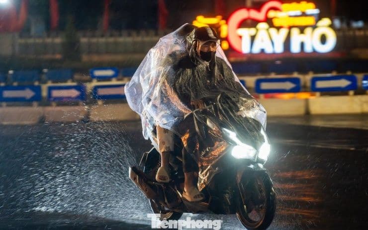 Người đi xe máy mặc áo mưa trong đêm mưa rét ở Hà Nội.