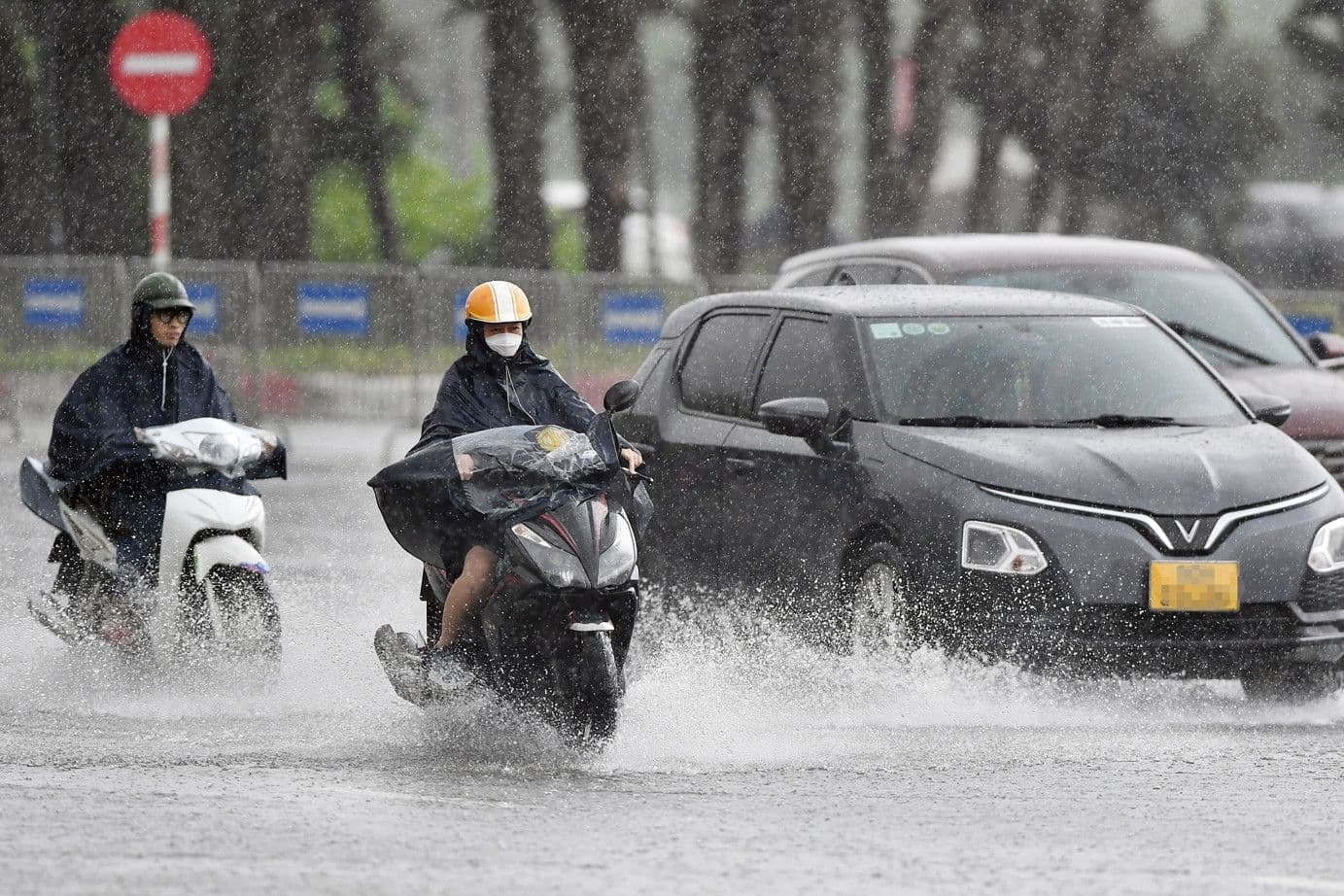 Người đi xe máy trong mưa lớn, minh họa hiện tượng thời tiết cực đoan do biến đổi khí hậu.