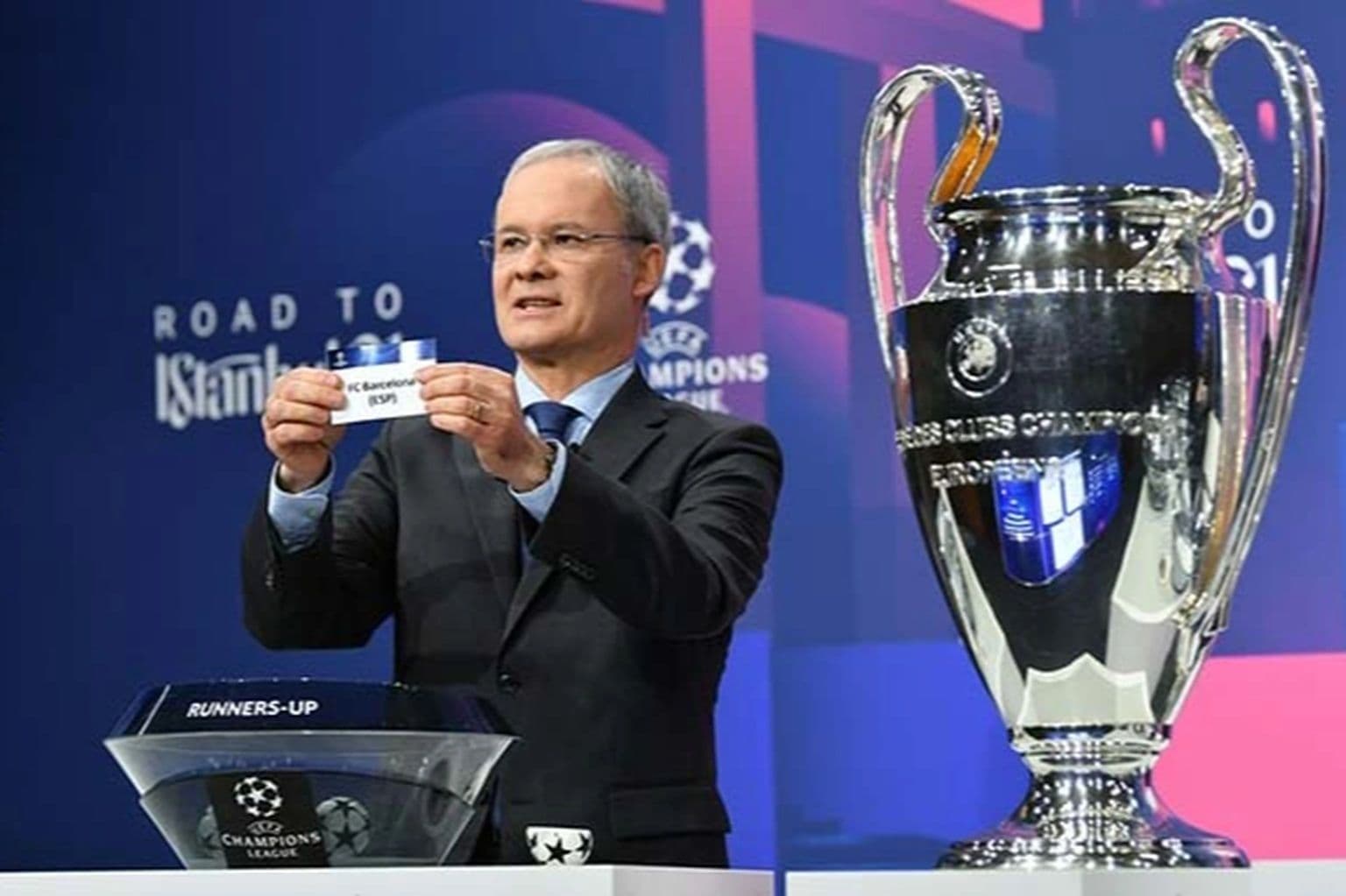 Người điều hành lễ bốc thăm Champions League cầm lá thăm đội Barcelona bên cạnh cúp bạc danh giá.