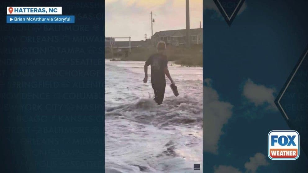 Người đàn ông bị sóng lớn từ bão Erin đánh vào bờ biển North Carolina, minh họa sức mạnh tàn phá của gió và biển.