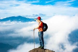 Người đàn ông đứng trên đỉnh núi nhìn ra xa và chỉ tay, tượng trưng cho việc định vị thị trường và tìm kiếm cơ hội.