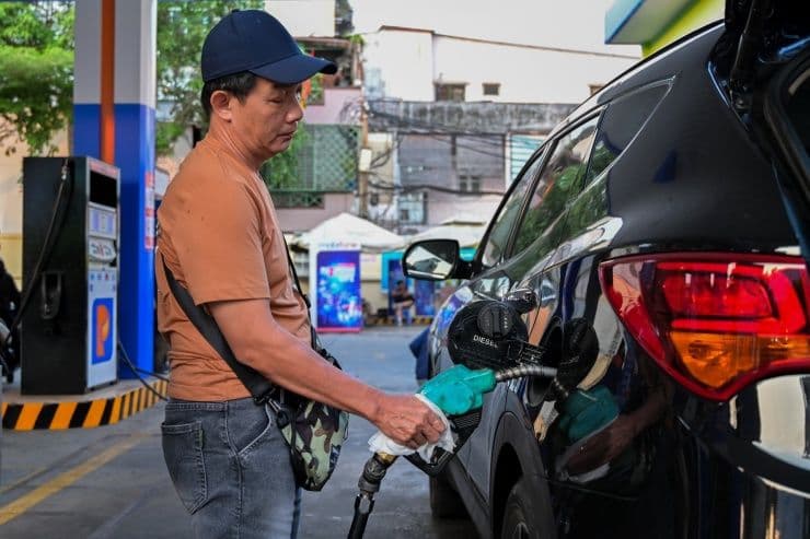 Người đàn ông đổ xăng vào ô tô tại trạm xăng, minh họa cho việc giá xăng dầu tăng mạnh và tác động đến đời sống.
