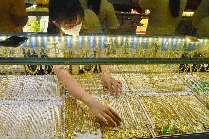 Người phụ nữ đang sắp xếp trang sức vàng trong tủ trưng bày tại cửa hàng DOJI, thể hiện sự sôi động của thị trường vàng Việt Nam.