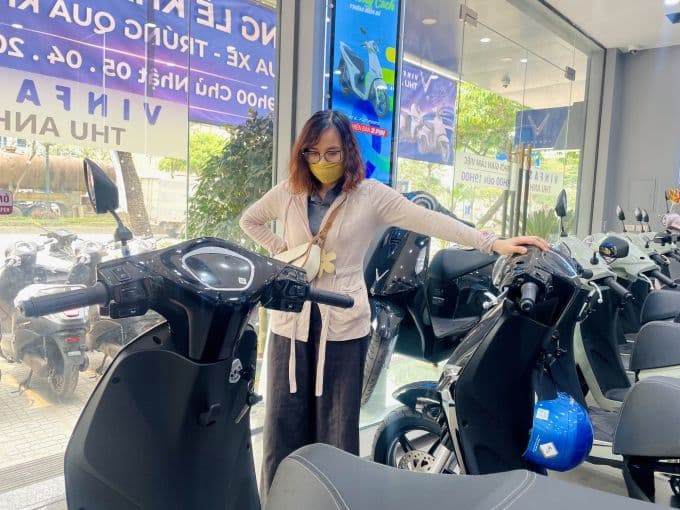 Người phụ nữ đang xem xét xe máy điện tại đại lý, minh họa sự tăng trưởng của thị trường xe điện Việt Nam.