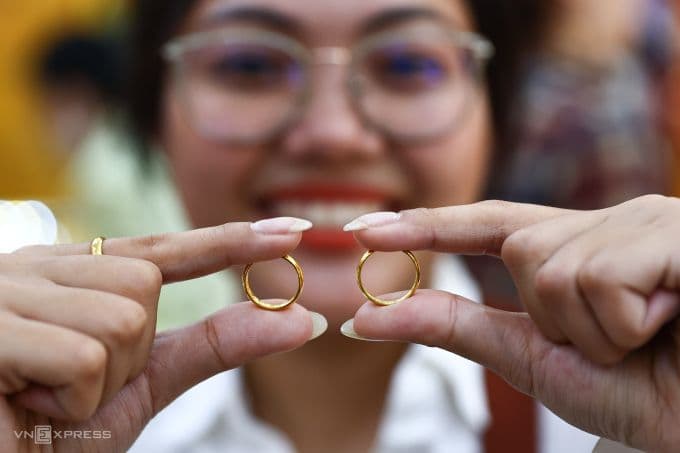 Người phụ nữ cầm hai chiếc nhẫn vàng trơn, tượng trưng cho sự tăng giá và cơ hội đầu tư vàng.