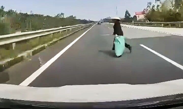 Người phụ nữ đi bộ băng qua đường cao tốc, minh họa cho những không gian không an toàn mà người đi bộ phải đối mặt trong đô thị Việt Nam.
