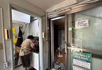 Người phụ nữ làm việc trong nhà với quạt điện, thể hiện một thói quen cá nhân để thích ứng với nắng nóng đô thị.