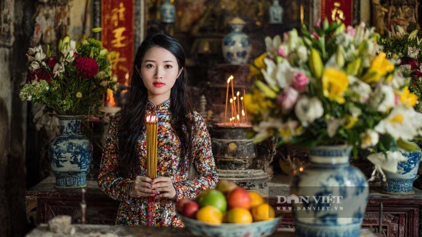 Người phụ nữ mặc áo dài cầm nén hương, thể hiện sự thành tâm cầu nguyện cho một năm mới hanh thông và thịnh vượng.