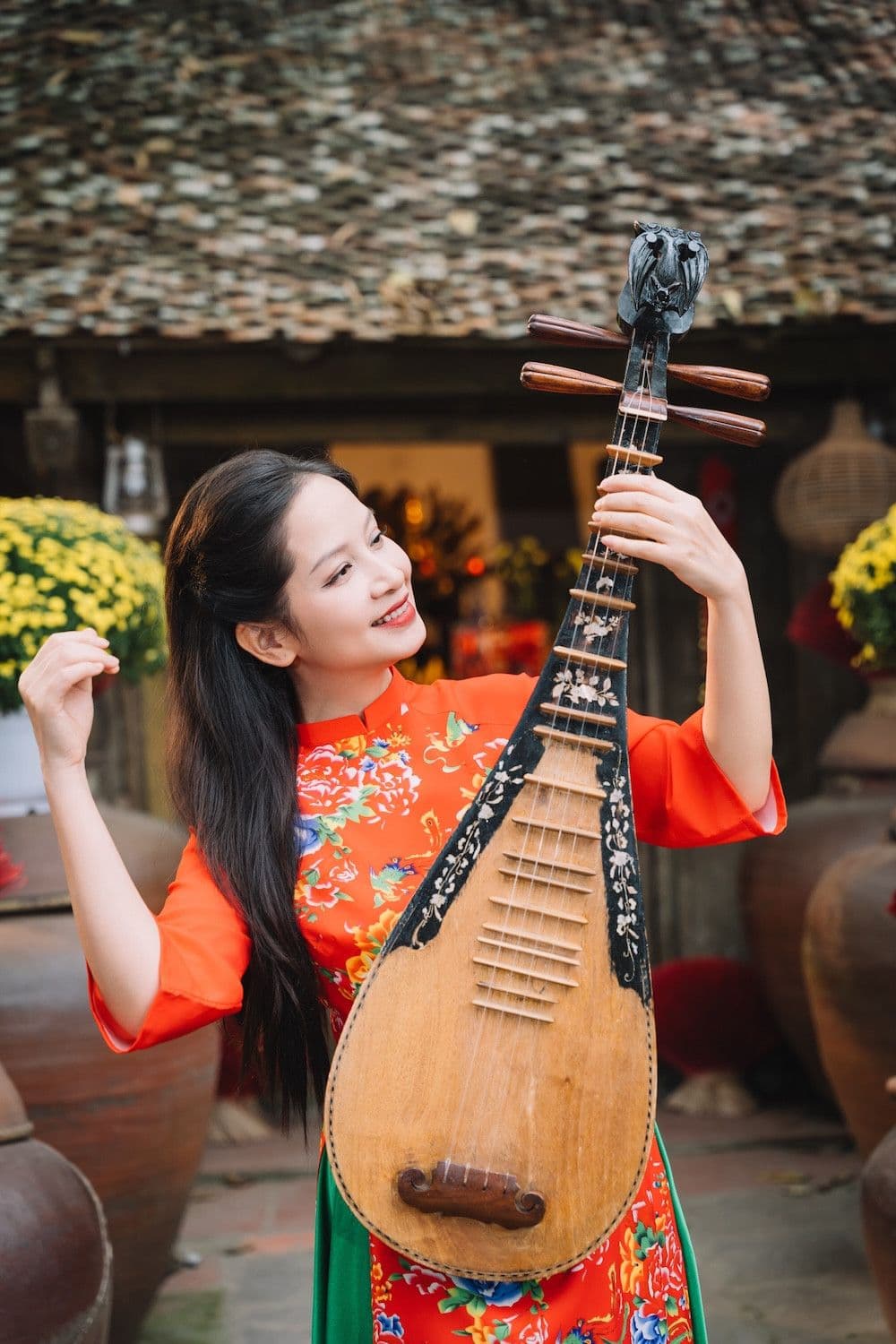 Người phụ nữ mặc áo dài truyền thống chơi đàn tỳ bà, tượng trưng cho sự hòa quyện giữa âm nhạc dân tộc và hơi thở hiện đại trong nhạc xuân.