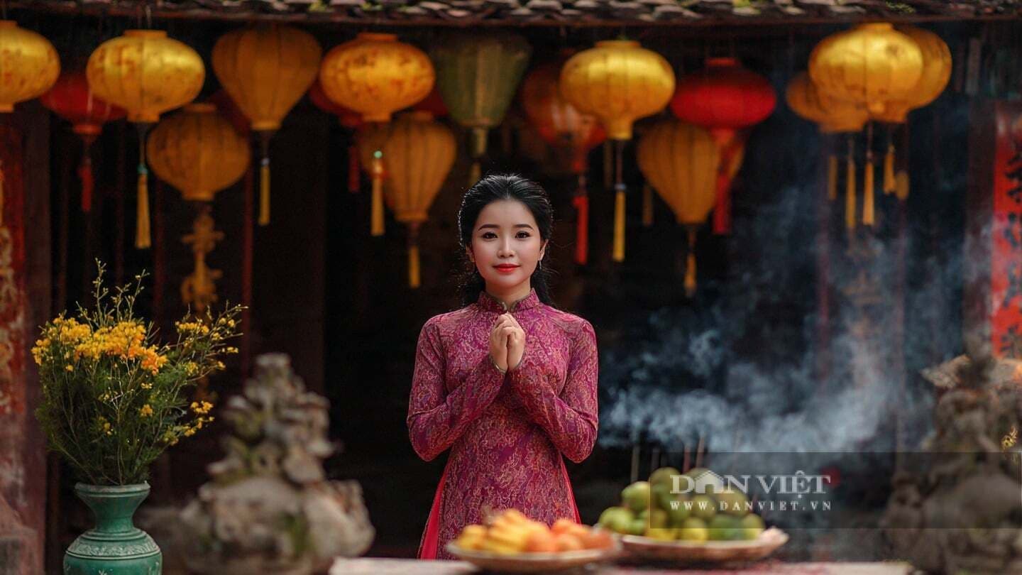 Người phụ nữ mặc áo dài truyền thống thành tâm khấn nguyện trước bàn thờ gia tiên.