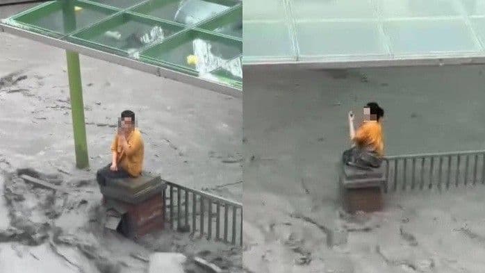 Người phụ nữ ngồi cô độc trên trụ cổng giữa dòng nước lũ và bùn lầy, thể hiện nỗi đau và sự tàn phá sau thiên tai.