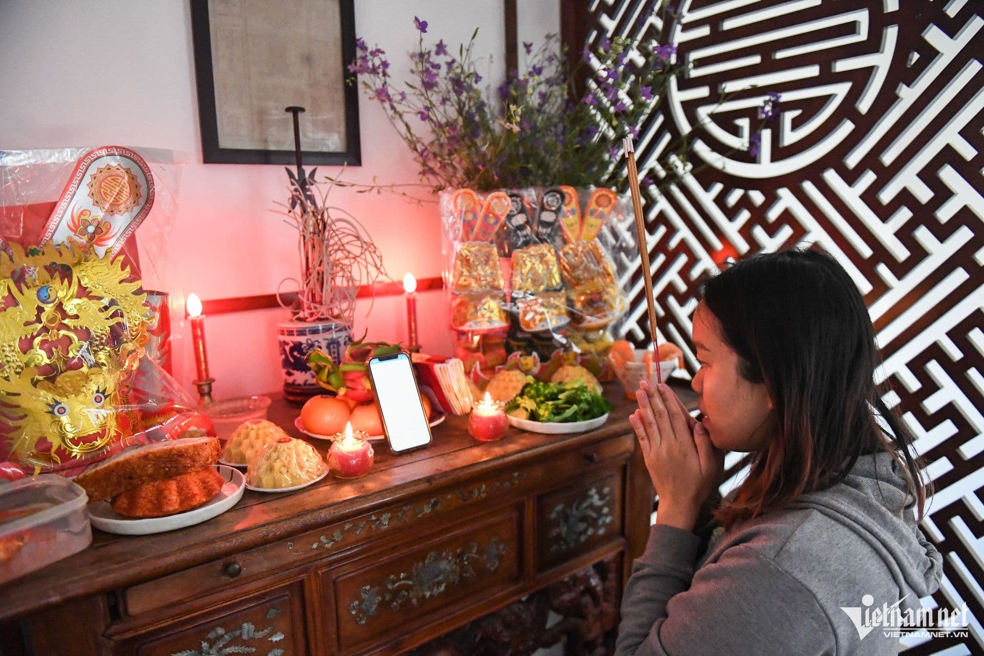 Người phụ nữ thành kính chắp tay cầu nguyện trước bàn thờ gia tiên trong lễ cúng Tất niên.