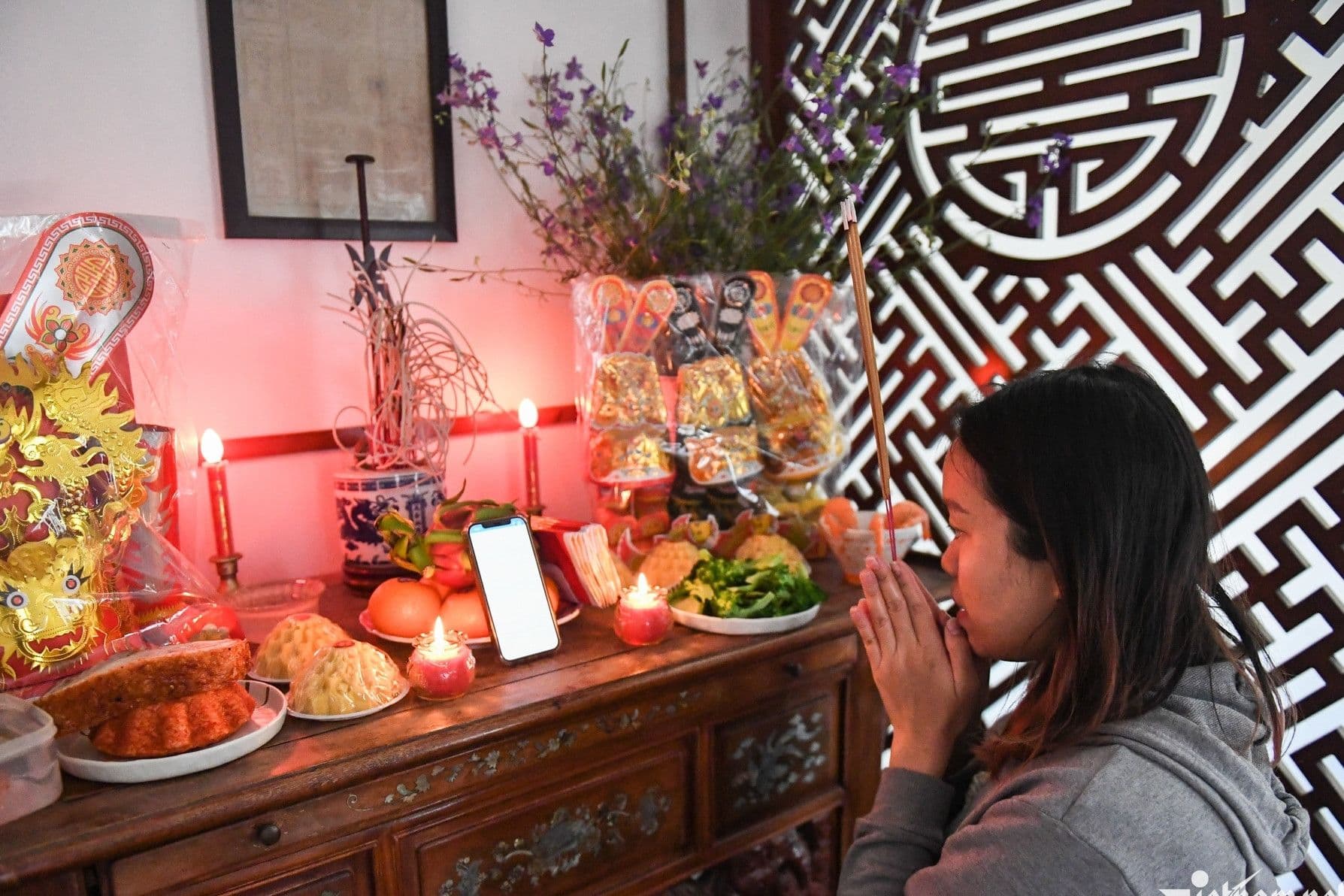 Người phụ nữ thành tâm khấn vái trước bàn thờ cúng ông Công ông Táo, thể hiện sự kết nối tâm linh.