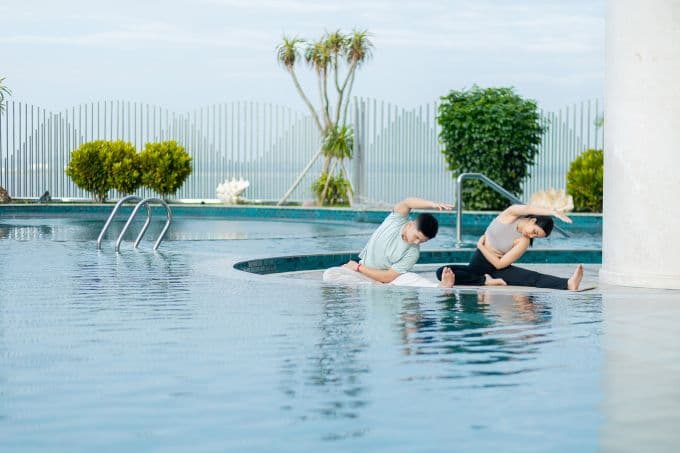 Người phụ nữ tập yoga trên bãi biển Hạ Long vào buổi sáng, tượng trưng cho trải nghiệm nghỉ dưỡng thư thái và khác biệt.