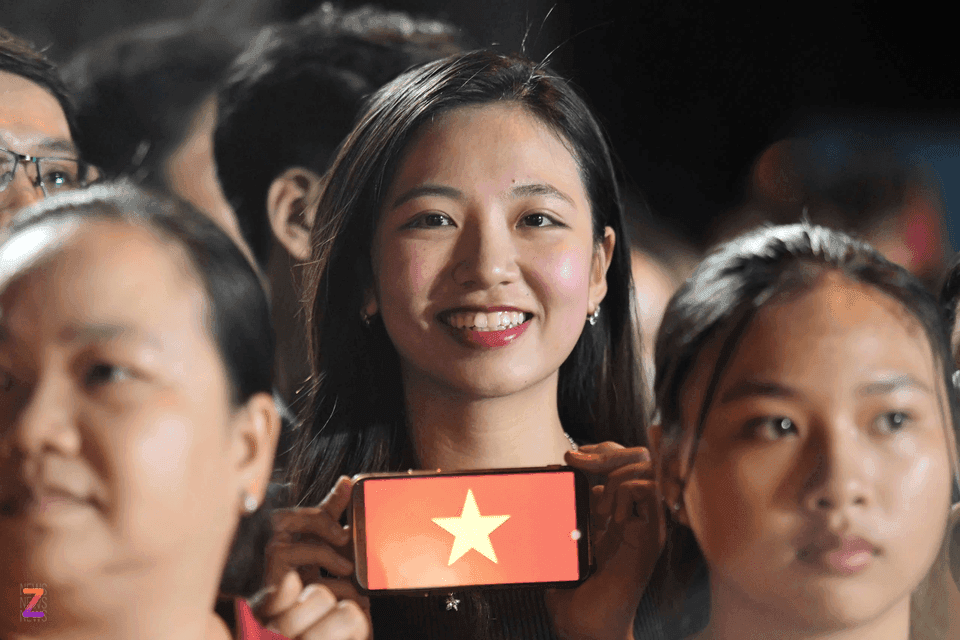Người phụ nữ trẻ mỉm cười cầm điện thoại có cờ Việt Nam, tượng trưng cho thế hệ số và tiềm năng của VNeID.