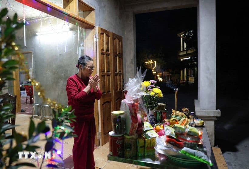 Người phụ nữ Việt Nam thành kính khấn nguyện trước bàn thờ cúng Tất Niên ngoài trời, thể hiện lòng tri ân tổ tiên và cầu mong bình an cho năm mới.