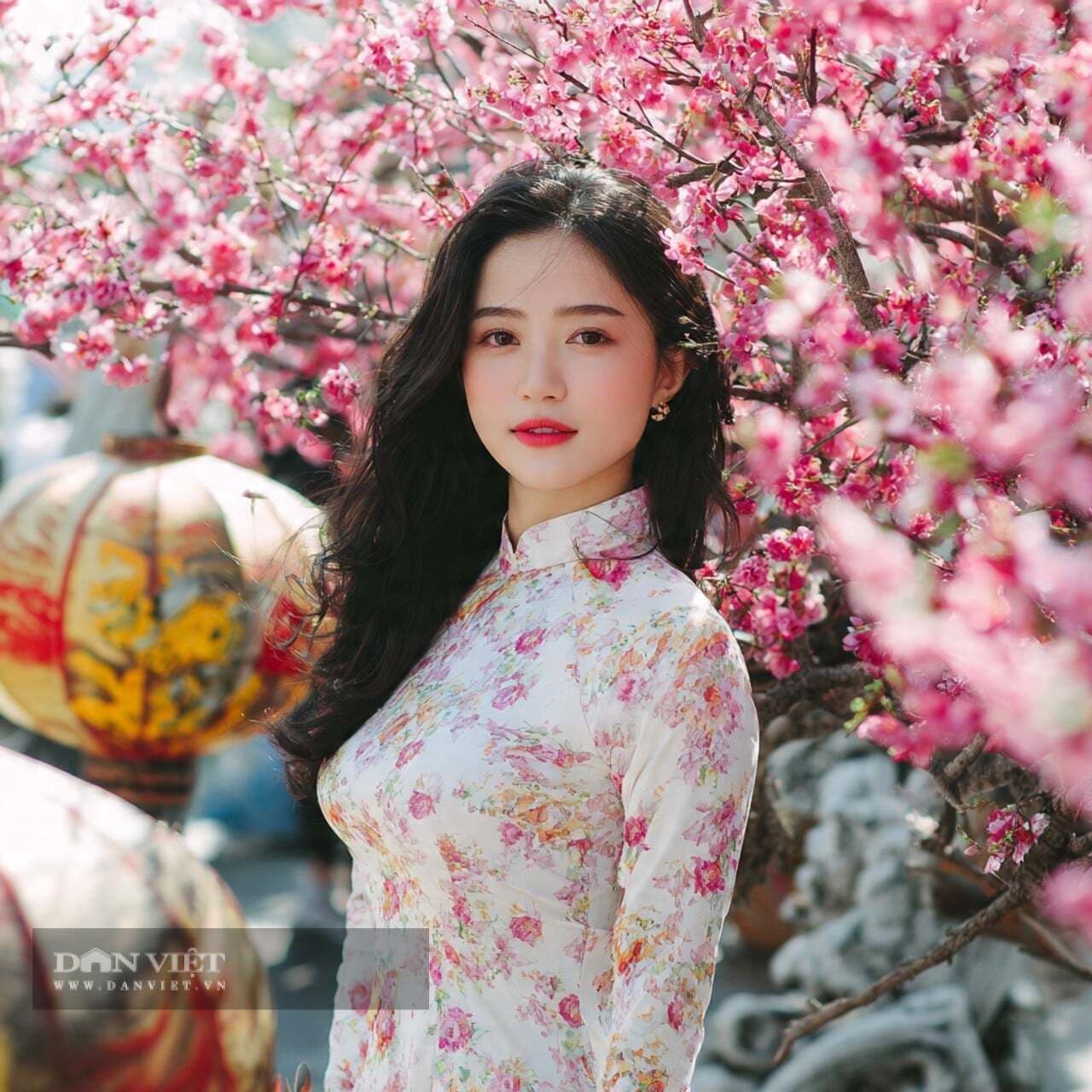 Người phụ nữ Việt Nam trong áo dài trắng giữa vườn hoa đào hồng, thể hiện sự hài hòa và năng lượng cá nhân.