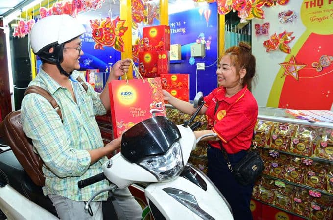 Người tiêu dùng mua sắm bánh Trung thu tại quầy hàng trang trí rực rỡ, thể hiện không khí mùa lễ hội