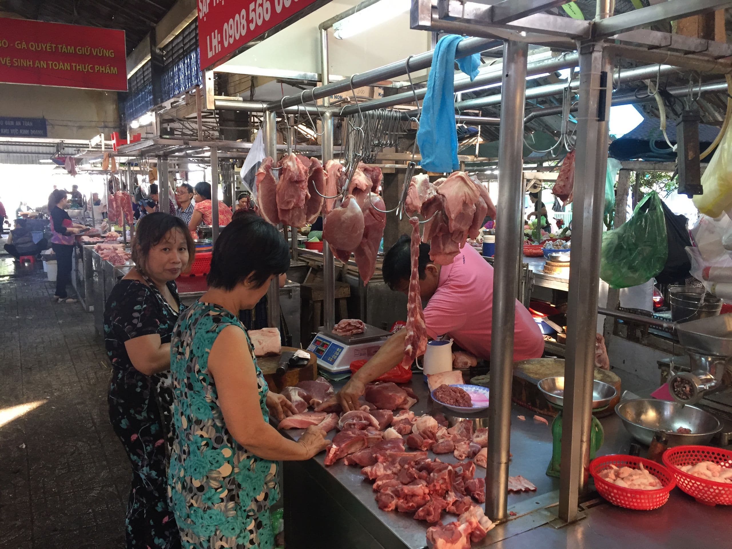 Người tiêu dùng mua thịt heo tại chợ dân sinh, phản ánh giá thịt bán lẻ vẫn cao dù giá heo hơi giảm sâu.