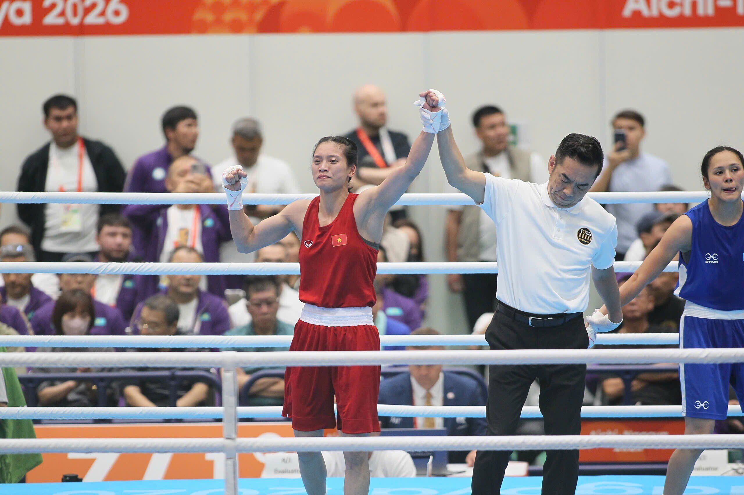 Nguyễn Thị Tâm giơ cao tay chiến thắng cùng trọng tài sau trận đấu boxing, biểu tượng cho bản lĩnh và ý chí kiên cường.