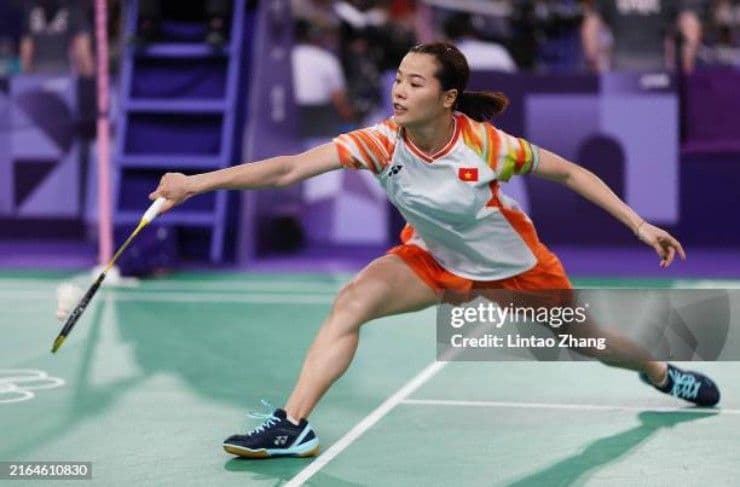 Nguyễn Thùy Linh trong trang phục thi đấu cầu lông, đang thực hiện cú đánh trên sân, thể hiện sự tập trung và bản lĩnh.