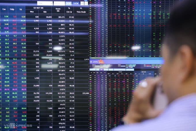 Nhà đầu tư theo dõi bảng điện tử chứng khoán, phản ánh biến động thị trường VN-Index giữa bão tố