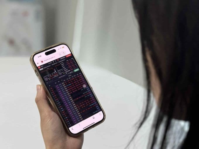Nhà đầu tư theo dõi thị trường chứng khoán giảm điểm mạnh trên điện thoại, phản ánh tâm lý lo lắng.