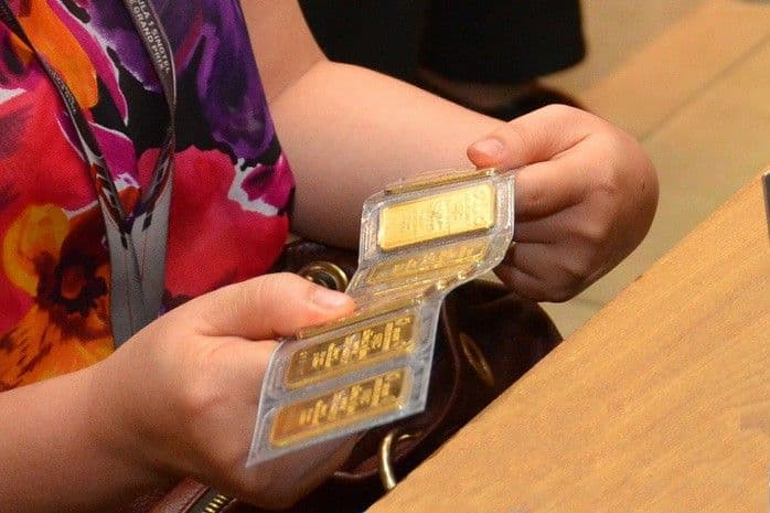 Nhà đầu tư xem xét các thỏi vàng vật chất, biểu tượng của tài sản trú ẩn an toàn.