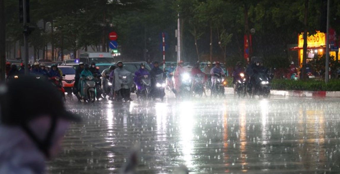 Nhiều người đi xe máy trong mưa lớn trên đường phố, nhấn mạnh sự cần thiết của sự tỉnh táo và chuẩn bị của cộng đồng.