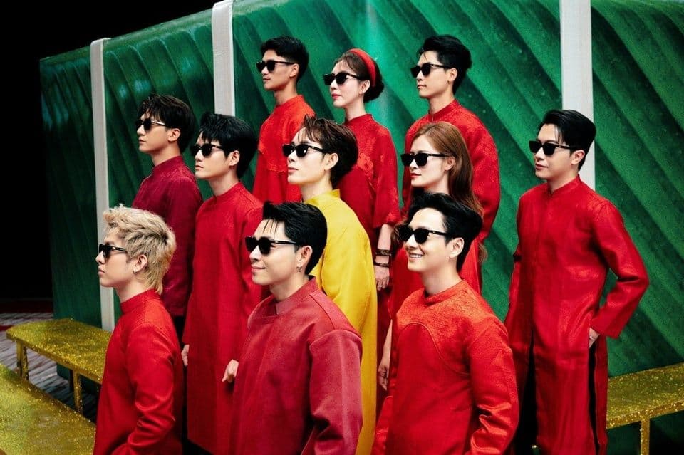 Nhóm nghệ sĩ trẻ mặc trang phục Tết hiện đại, đeo kính râm, thể hiện sự hợp tác giữa âm nhạc và thương hiệu trong mùa Tết.