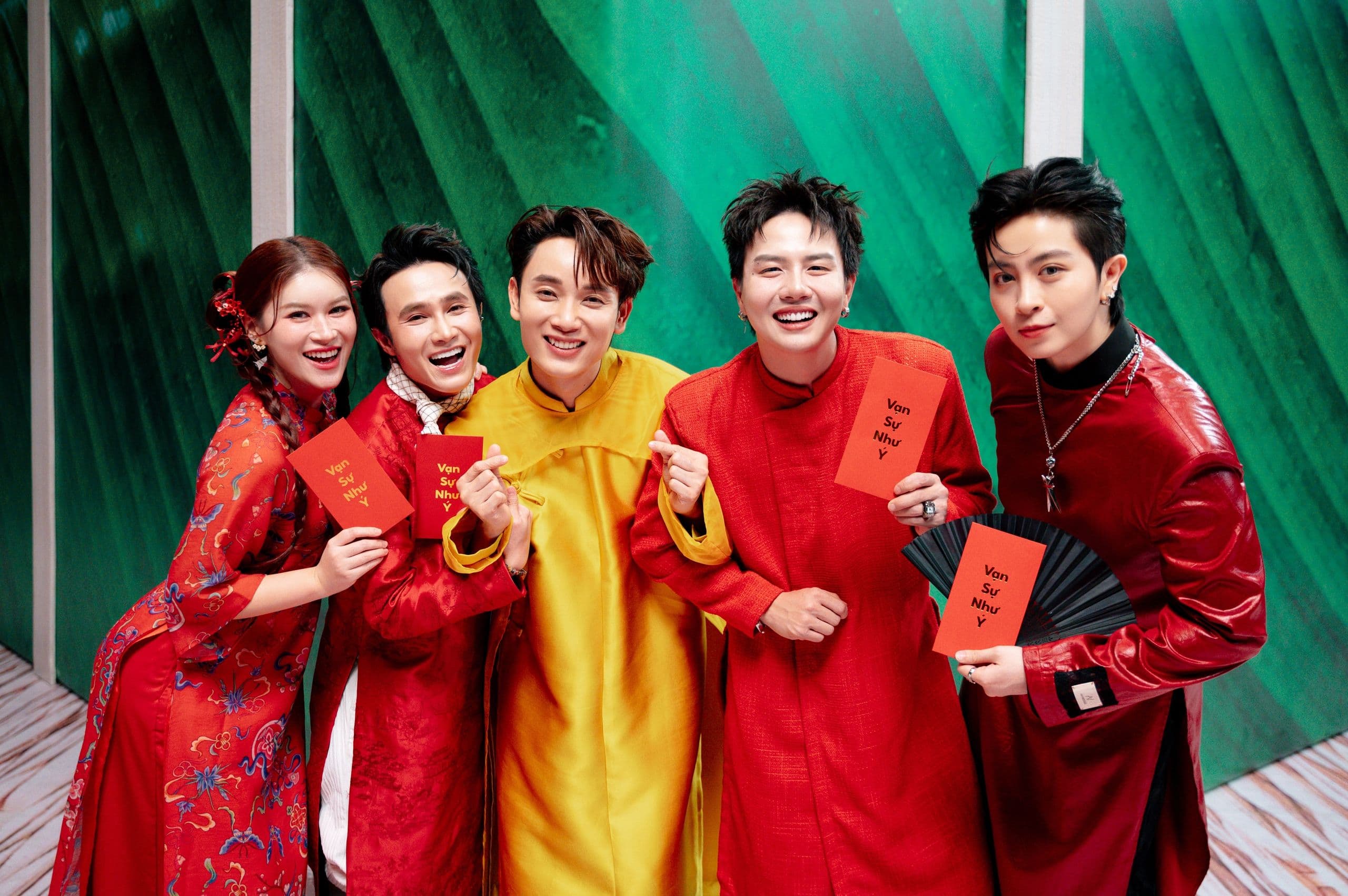Nhóm nghệ sĩ trẻ Việt Nam mặc trang phục Tết truyền thống và hiện đại, tươi cười cầm bao lì xì 'Vạn Sự Như Ý', tượng trưng cho sự đổi mới trong nhạc xuân.