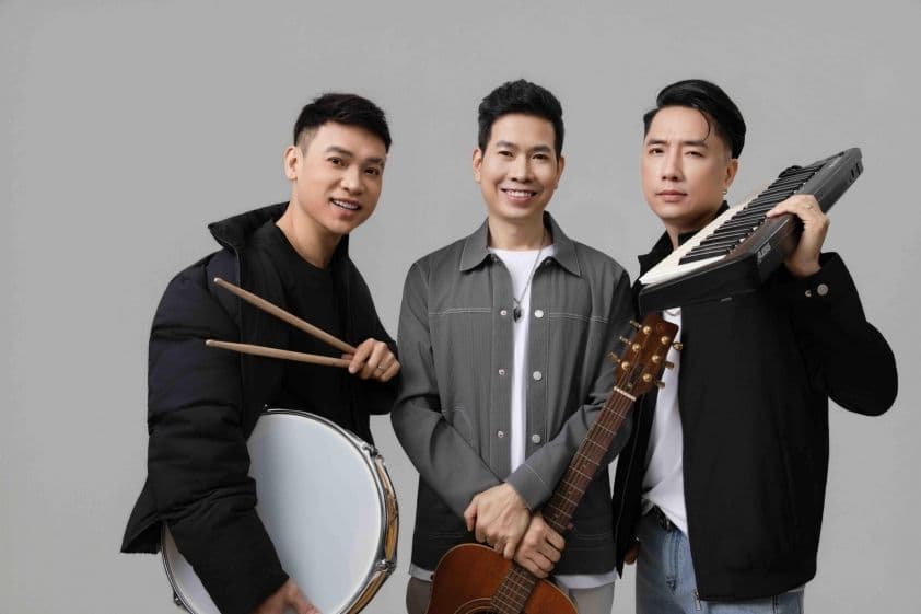 Nhóm nhạc Tre Papa trong trang phục hiện đại, cầm nhạc cụ như trống, guitar và keyboard, tượng trưng cho sự kết hợp giữa truyền thống và hiện đại trong nhạc xuân.