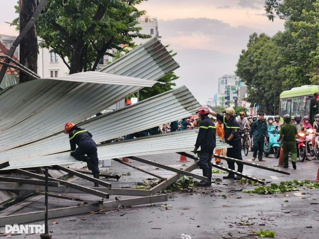Nhân viên cứu hộ đang dọn dẹp mái tôn bị gió cuốn trên đường phố, minh họa thiệt hại do thời tiết khắc nghiệt và hành vi đối phó.