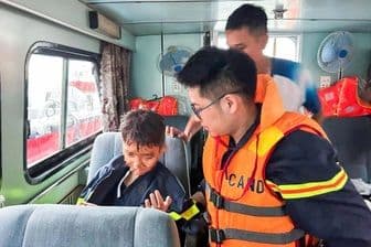 Nhân viên cứu hộ hỗ trợ một đứa trẻ thoát khỏi khu vực nguy hiểm sau thảm kịch lật tàu Hạ Long.