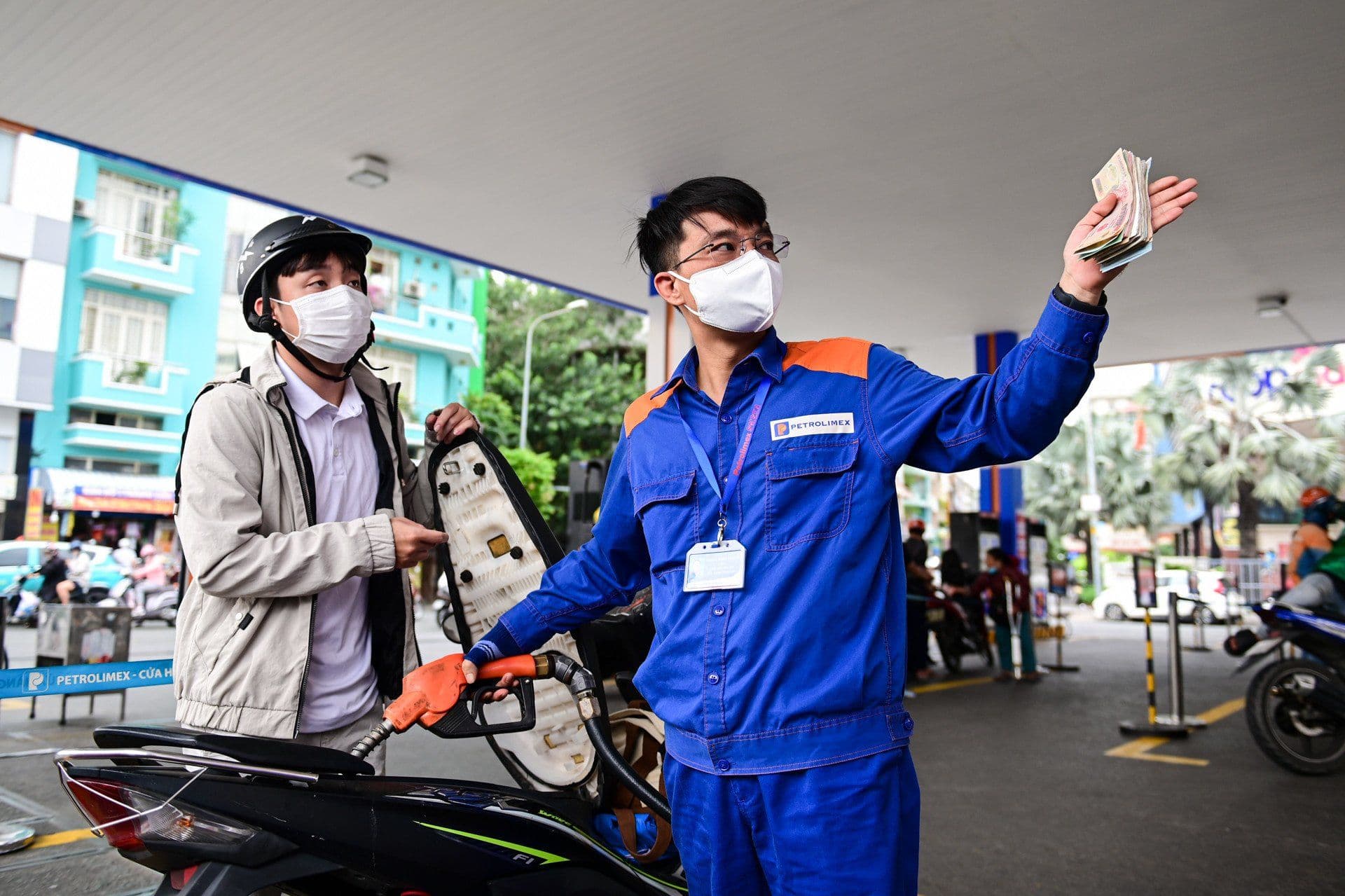 Nhân viên cây xăng đang giao dịch với khách hàng, thể hiện sự tương tác giữa người bán và người mua trong bối cảnh giá xăng dầu biến động.