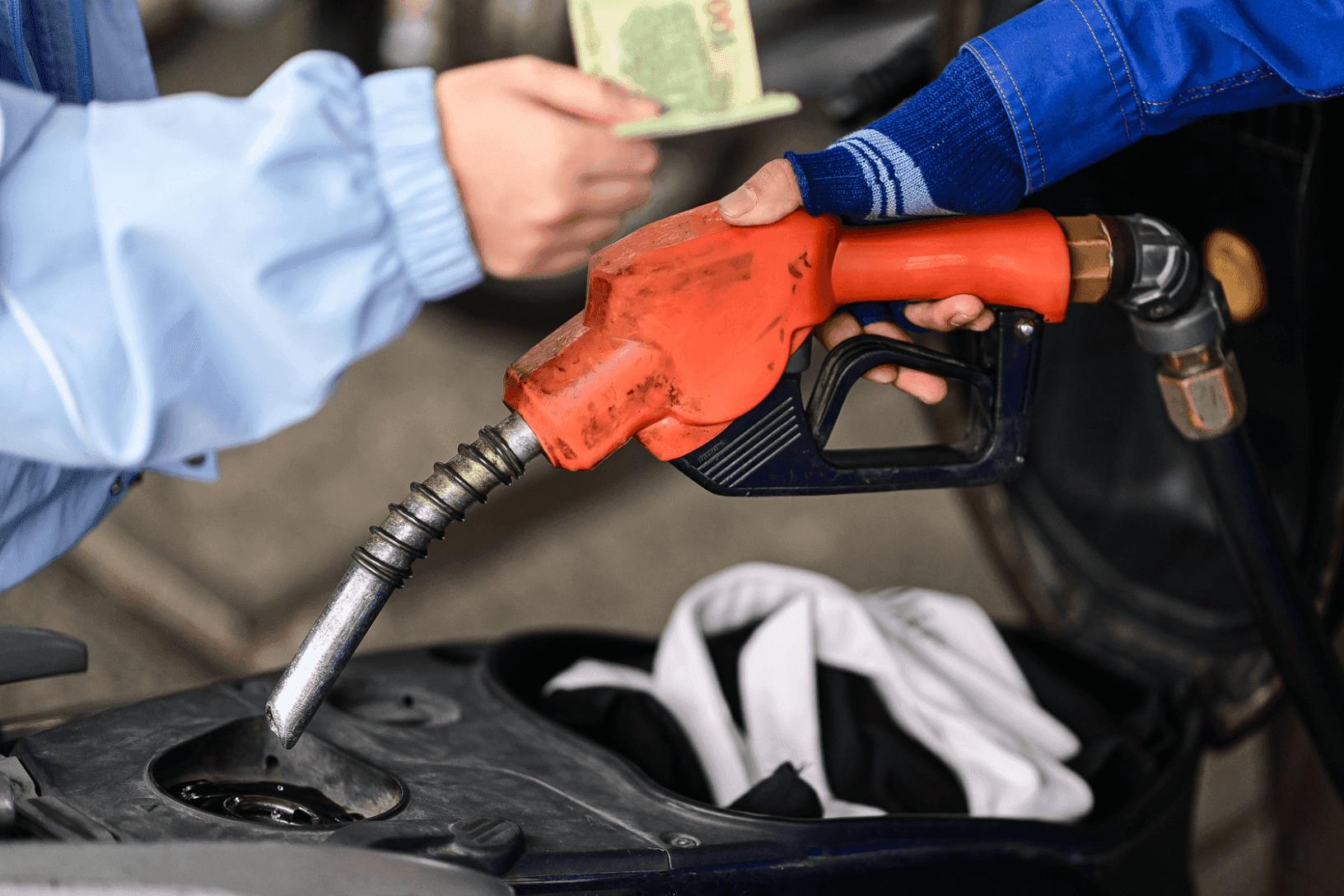 Nhân viên cây xăng đang đổ xăng cho xe máy, khách hàng thanh toán tiền, minh họa giá xăng dầu và giao dịch tiêu dùng.