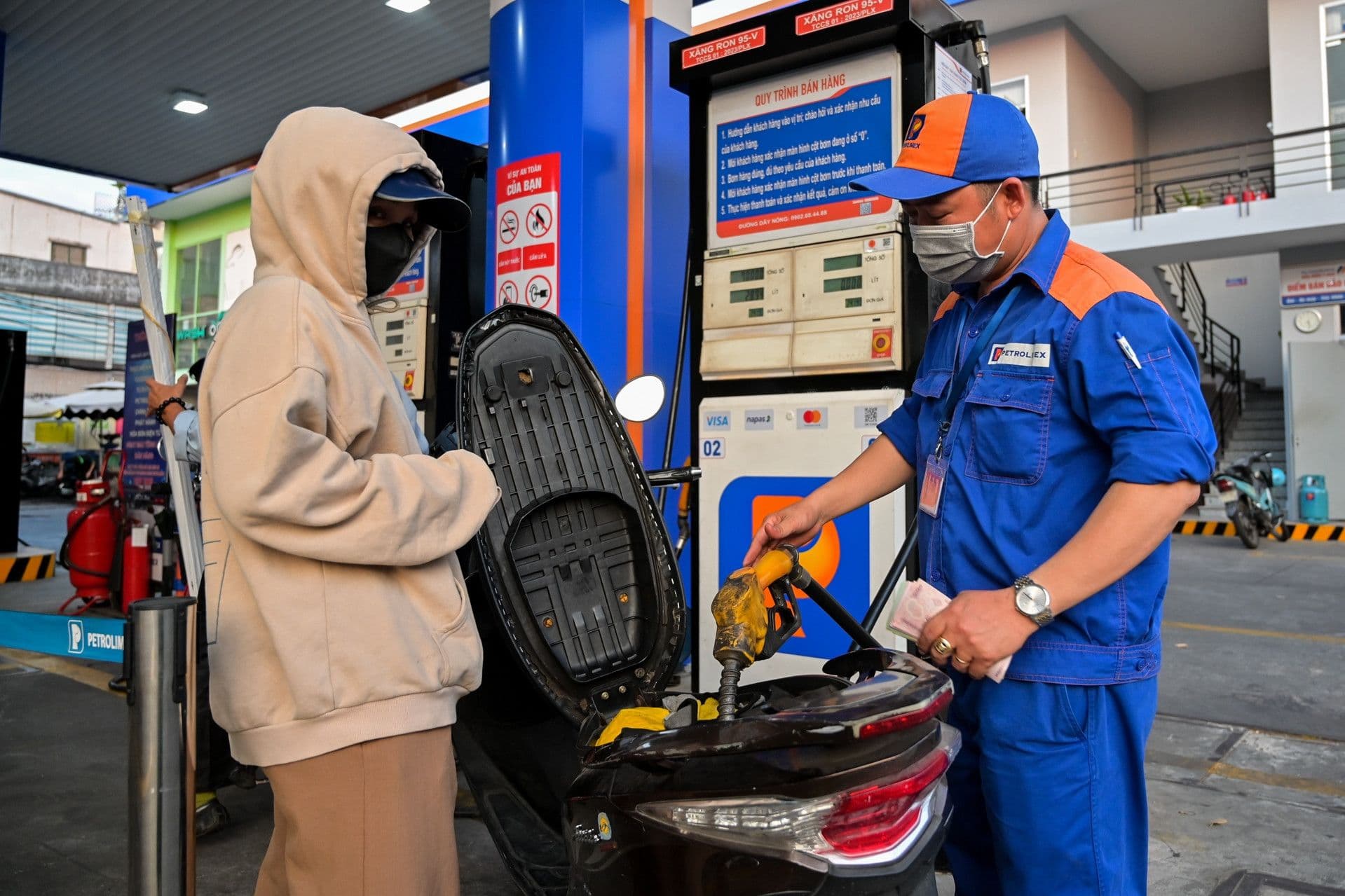 Nhân viên cây xăng đang đổ xăng cho xe máy, thể hiện hoạt động cung ứng nhiên liệu và nỗ lực ổn định thị trường.