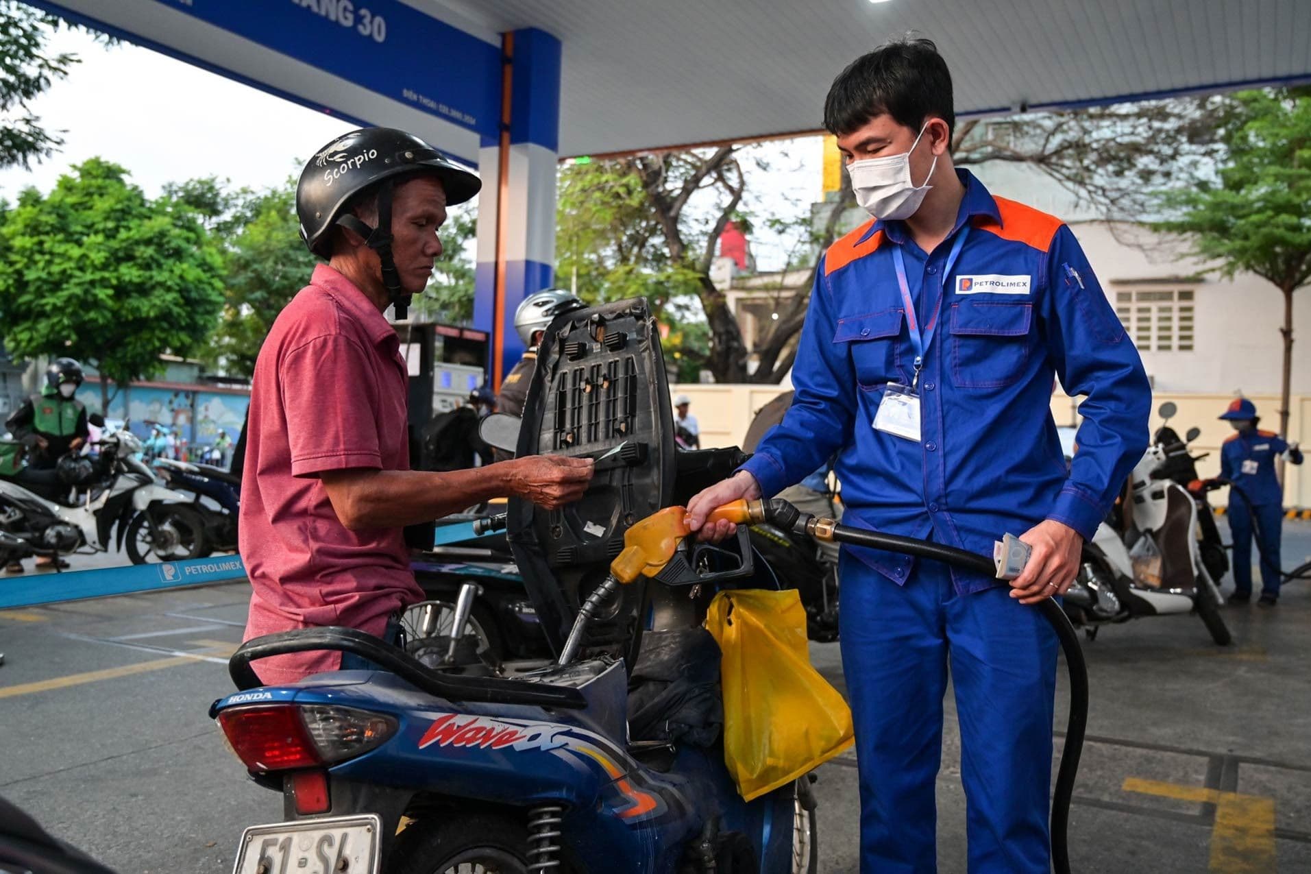 Nhân viên cây xăng đổ xăng cho xe máy, minh họa giá xăng dầu giảm.