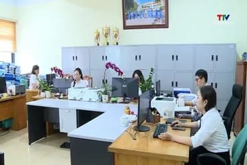 Nhân viên văn phòng đang làm việc với máy tính và hồ sơ, thể hiện hoạt động kinh doanh và quản lý hóa đơn.