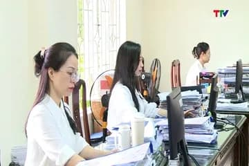 Nhân viên văn phòng đang làm việc với máy tính và hồ sơ, tượng trưng cho công tác quản lý thuế và nỗ lực làm sạch mã số thuế để chống gian lận hóa đơn.