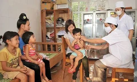Nhân viên y tế chăm sóc trẻ em, minh họa chính sách y tế cơ sở và những tác động thực tế của nó.