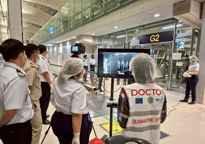 Nhân viên y tế tại sân bay châu Á kiểm tra thân nhiệt hành khách bằng máy quét nhiệt để phòng chống virus Nipah.