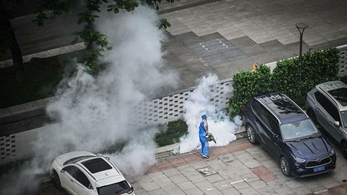 Nhân viên y tế Trung Quốc phun thuốc diệt muỗi diện rộng tại khu dân cư để kiểm soát dịch Chikungunya, thể hiện phản ứng 'cấp độ Covid'.